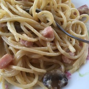 Spaghetti noodles, ham, and mushrooms swim in a creamy garlic sauce made from cream and eggs and cheese.