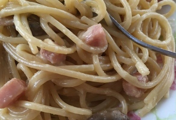 Spaghetti noodles, ham, and mushrooms swim in a creamy garlic sauce made from cream and eggs and cheese.