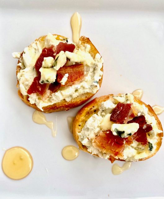 Bacon & Blue Cheese Crostinis -- Crispy, seasoned and toasted baguette slices schmeared with a flavorful blue cheese and cream cheese combination, topped with salty bacon, and drizzled with honey. | thatwhichnourishes.com