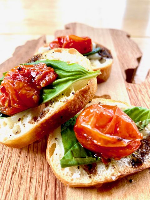 Roasted Tomato Caprese Crostinis -- Melted Mozzarella atop a perfect slice of toasted and seasoned baguette layered with fresh basil, a tart and garlicky roasted tomato, and drizzled with a balsamic glaze. | thatwhichnourishes