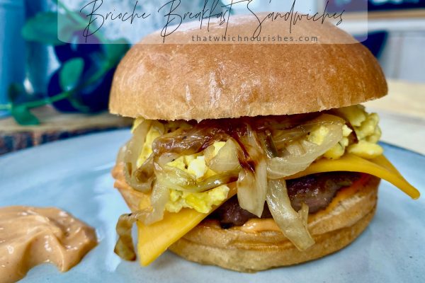 Brioche Breakfast Sandwiches -- a soft brioche bun surrounding melty cheese, thick cut Canadian bacon or a savory sausage patty topped with the creamiest scrambled eggs you've ever had, finished with caramelized onions and the perfect hint of flavor and heat in a swipe of sriracha mayo. | thatwhichnourishes.com